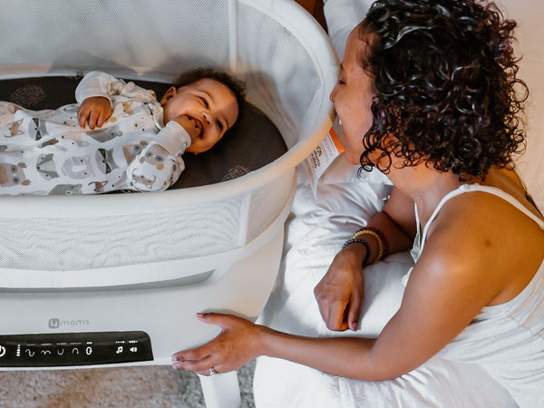 Baby in 4moms MamaRoo Sleep Bassinet while parent watches