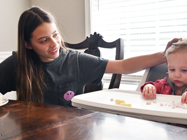 Sibling next to baby eating in 4moms Connect High Chair