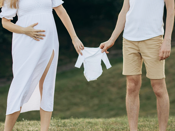 Expecting parents holding baby onesie