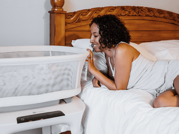 Parent looking at baby in 4moms MamaRoo Sleep Bassinet